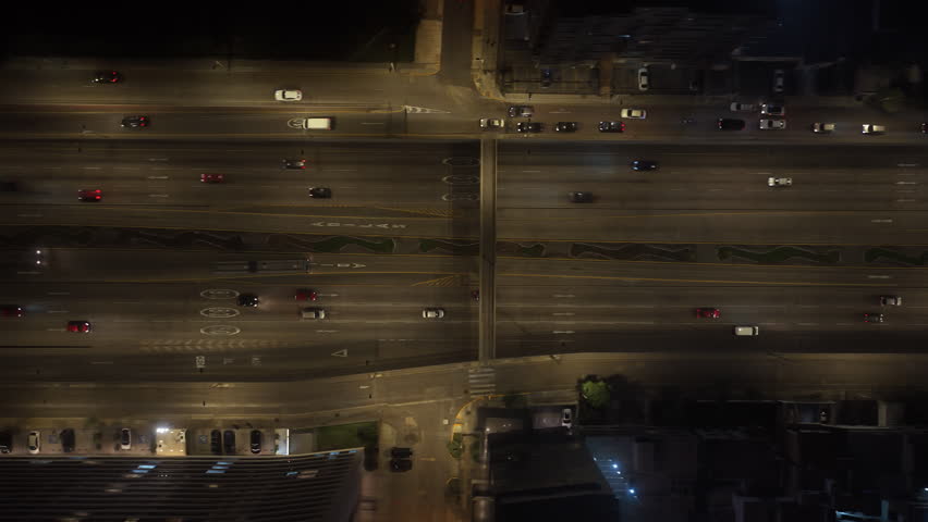 Aerial top down view of a bustling highway in Lima, Peru at night. Cars with headlights on travel along the illuminated roads