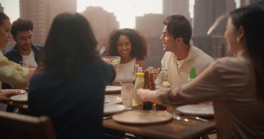 Vibrant Group of Friends and Family Gathers on a Rooftop, Enjoying Lively Conversations and Laughter. They Share Drinks and Delicious Food, Celebrating Getting togeher