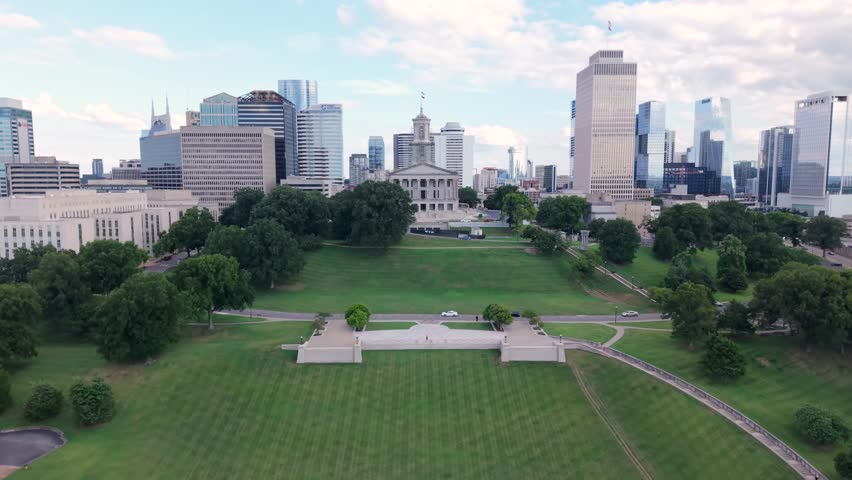 Downtown Nashville, Tennessee city skyline with a view of the state capitol building, Snow Sled Hill, and Victory Park - ascending aerial reveal