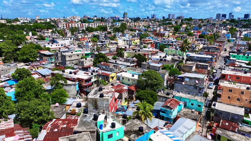 Aerial view of a suburban area in Santo Domingo, Dominican Republic. The outskirts of the city with peeling roofs and narrow streets. This is a residential area with many buildings and trees.