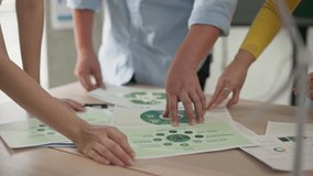 Close-up shot of diverse team members reviewing, pointing at green ESG project documents during a collaborative meeting. Focus on charts and data related to climate action and sustainability. - Powered by Shutterstock - Get 15% off with code: PIKWIZARD15