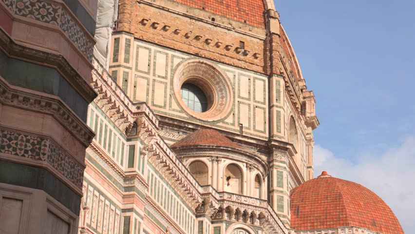 Cathedral dome and campanile rising above rooftops of Florence under clear blue sky in renaissance city