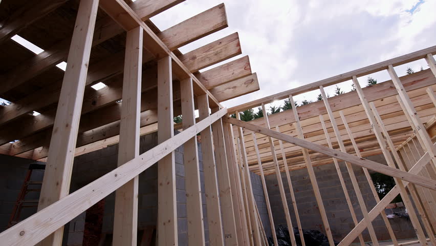Construction workers frame wooden roof structure on building site with rafters structure beams