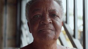 Portrait Of Elderly Woman Looking Directly At Camera With Neutral Expression, Standing Near Garage Iron Bars In Natural Light During Calm Moment At Home - Powered by Shutterstock - Get 15% off with code: PIKWIZARD15