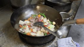 Chef cooking stir-fried beef with fresh mixed vegetables in a hot wok inside a Thai restaurant kitchen. The vibrant dish includes broccoli, mushrooms, carrots, and cauliflower tossed with savory sauce - Powered by Shutterstock - Get 15% off with code: PIKWIZARD15
