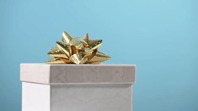 Gift box with golden bow turns on blue background. - Powered by Shutterstock - Get 15% off with code: PIKWIZARD15