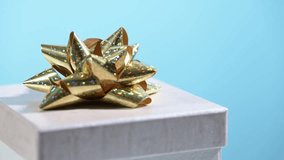 Gift box with golden bow turns on blue background. - Powered by Shutterstock - Get 15% off with code: PIKWIZARD15
