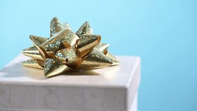 Gift box with golden bow turns and blurs on blue background. - Powered by Shutterstock - Get 15% off with code: PIKWIZARD15