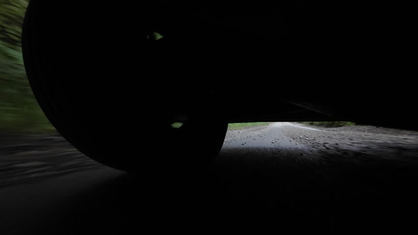 Low-mounted action-cam view of a car accelerating up a dip on a shaded country road in Sevenoaks, Kent, United Kingdom.