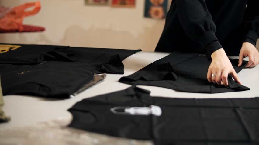 Tailor folding and marking black fabric on worktable in sewing studio