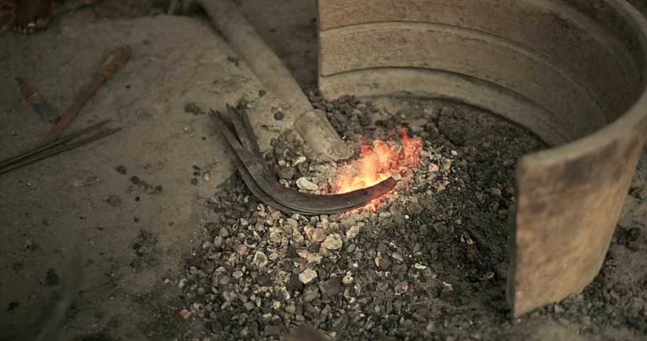 Traditional blacksmiths forging iron farming tools in rural India