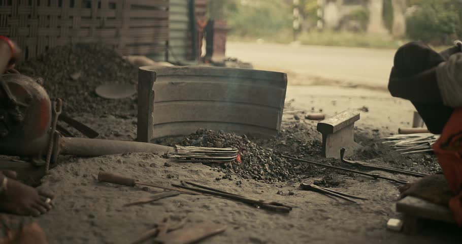Traditional blacksmiths forging iron farming tools in rural India