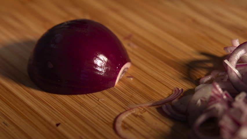 Chef slicing fresh red onion on wooden cutting board. Media
