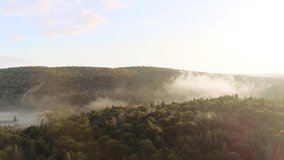 Misty Forest Hills Illuminated by Sun Rays. A beautiful shot of two forested hills with mist rising from the shadowed depression between them, illuminated by golden sun rays. - Powered by Shutterstock - Get 15% off with code: PIKWIZARD15