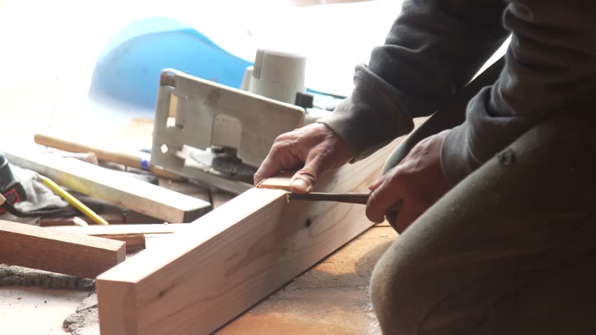 A man carving wood with a chisel.
