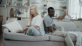Multiethnic married couple after quarrel at home, interracial marriage. Beautiful blonde woman and black man sitting on couch back to back, african american and caucasian ethnicity, love relationship - Powered by Shutterstock - Get 15% off with code: PIKWIZARD15