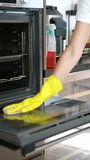 A professional cleaner wearing yellow gloves carefully wipes the oven door with a cloth and cleaning spray during kitchen deep cleaning
 - Powered by Shutterstock - Get 15% off with code: PIKWIZARD15