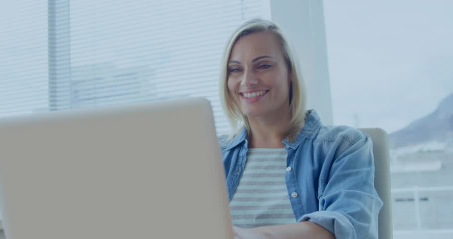 Woman sitting at desk and typing on laptop, visualizing business data with animated charts, smiling. Technology, analytics, innovation, digital, productivity, modern, workspace