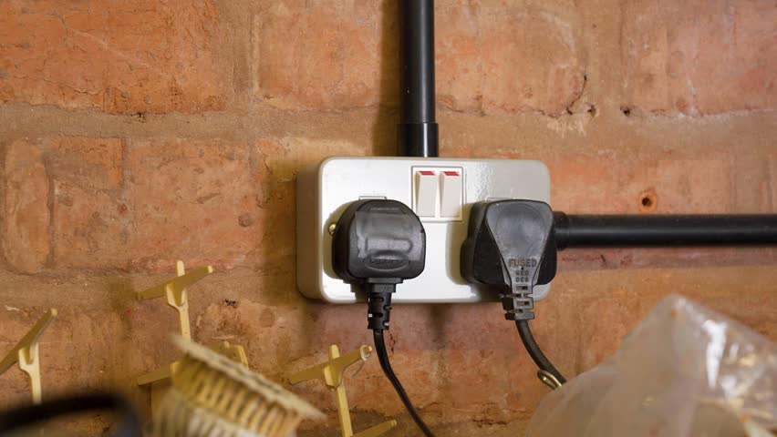 Hand switch off and unplugging a plug from the socket outlet in a garage, conserving power usage and electricity