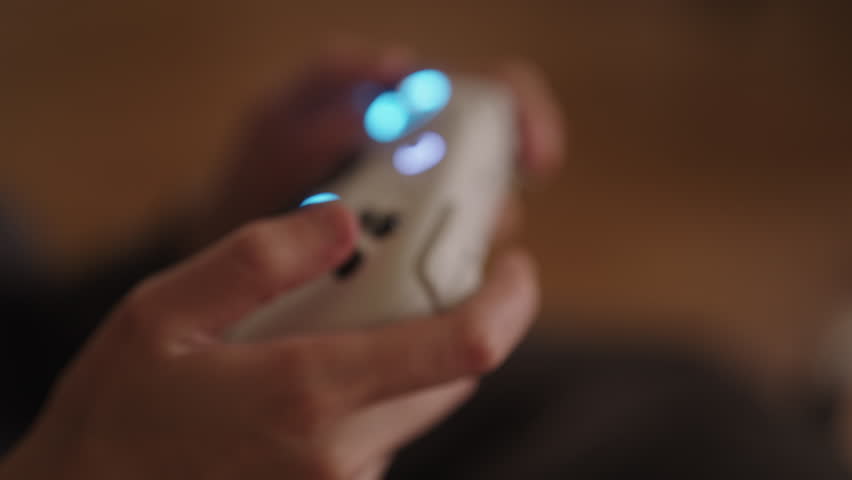 Close-up hands of unrecognizable woman using modern gaming controller with illuminated blue joysticks, engaging in digital entertainment, highlighting immersive gaming and interactive technology.