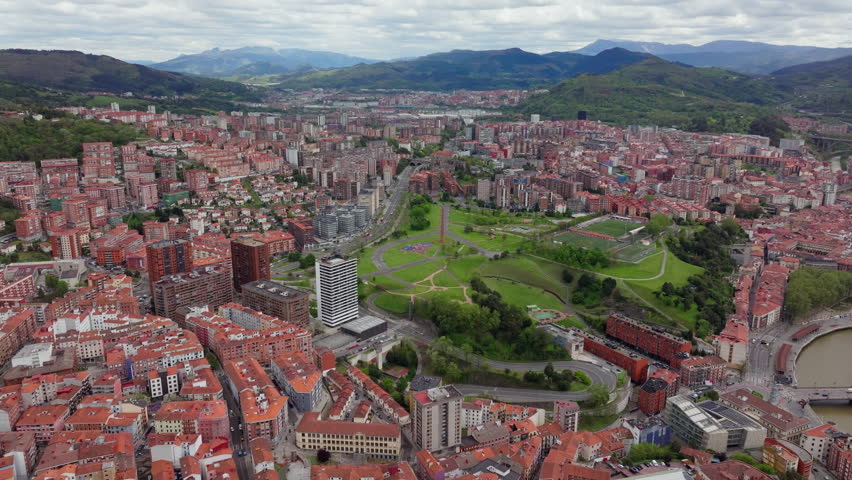 Tripod shot from a unique high-altitude perspective of Bilbao, Spain. Cityscape, Etxebarria Park, majestic mountains enveloping the area