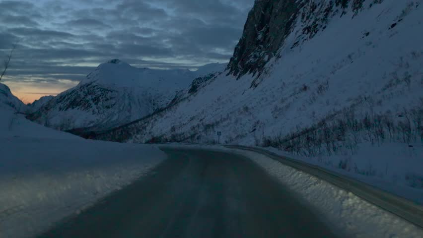 Driving through snowy Norwegian fjord at sunset