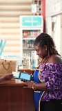 Vertical Video, Contactless payment, African businesswoman processing cashless transactions for a customer in her supermarket via point of sale POS device - Powered by Shutterstock - Get 15% off with code: PIKWIZARD15