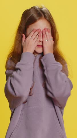 Don't want to look at this, awful. Afraid shocked preteen child girl kid closing eyes with hand showing stop gesture, confused shy scared reject to watch. Teen children isolated on yellow background