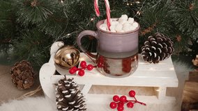 Holiday festive setup featuring clay mug of hot chocolate, marshmallows, candy cane, pinecones, red berries, golden accents, and lush green branches, celebrating Christmas magic. - Powered by Shutterstock - Get 15% off with code: PIKWIZARD15