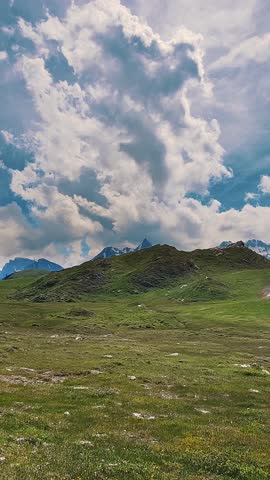 Alpine Landscape with Lush Meadows Under a Cloudy Sky Perfect for Nature-Themed Design Projects