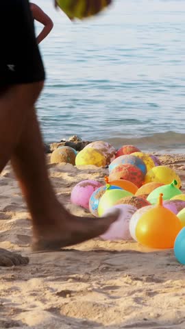 On the beach, on the sand are balloons filled with water instead of air. people having a rest playing fun games on the beach