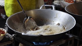 A chef stir-fries thin vermicelli noodles with various ingredients in a steaming wok over a blue gas flame, capturing vibrant Asian street food cooking. - Powered by Shutterstock - Get 15% off with code: PIKWIZARD15