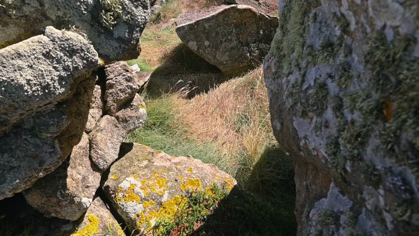 Camera movement revealing the stunning and rugged coastline of Galicia, Spain, where turquoise ocean waves crash against the rocks on a sunny day, showcasing a powerful and wild natural landscape