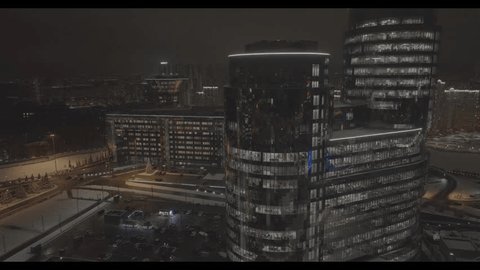 Drone Flying Backward over Illuminated Glass Towers