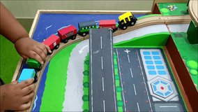 A child playing with colorful wooden toy trains on a miniature railway track. Perfect concept for childhood, learning, and early development themes - Powered by Shutterstock - Get 15% off with code: PIKWIZARD15