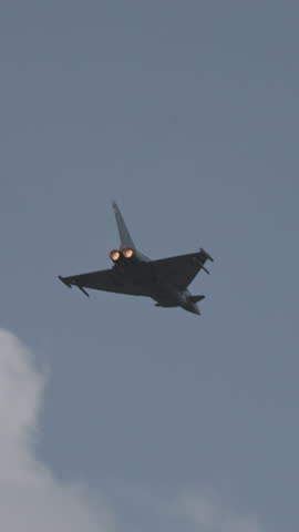 Fast fighter jet during high speed combat maneuvers with clouds