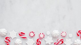 Red and white Christmas sweets bottom border. Top view, stop motion loop video on a white marble background with copy space. Peppermint, candy cane, snowflake candies. - Powered by Shutterstock - Get 15% off with code: PIKWIZARD15