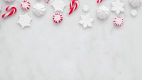 Red and white Christmas sweets top border. Above view, stop motion loop video on a white marble background with copy space. Peppermint, candy cane, snowflake candies. - Powered by Shutterstock - Get 15% off with code: PIKWIZARD15