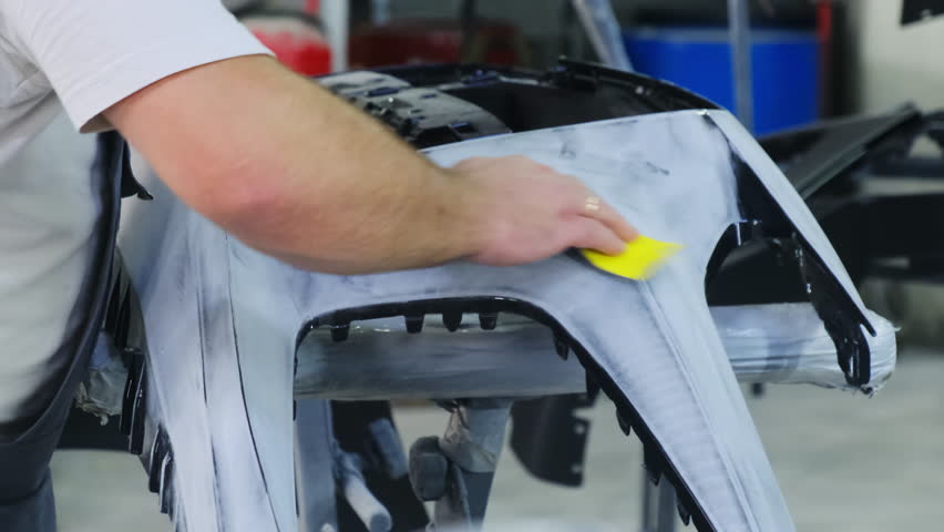 Mechanic hand polishes car body detail with sandpaper sheet in workshop closeup. Man worker renovates damaged vehicle part at service station - Powered by Shutterstock - Get 15% off with code: PIKWIZARD15