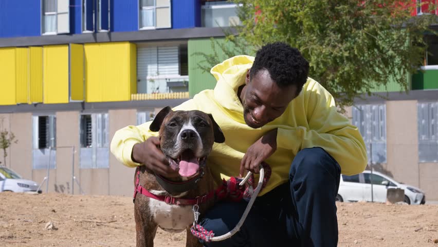African american man petting his dog in a colorful neighborhood