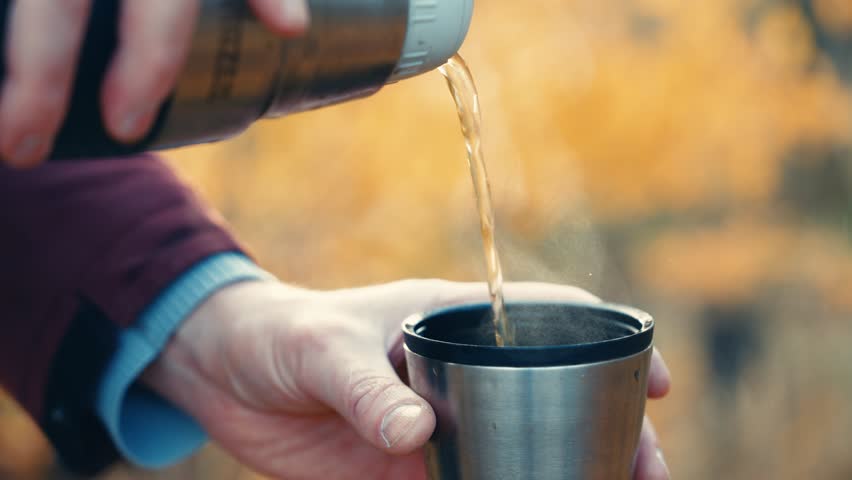 Man Pouring Hot Drink from Thermos Flask into Cup | Autumn Outdoor Camping Coffee Break | Close-Up Hands Holding Stainless Steel Travel Mug