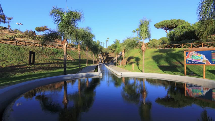 Peaceful path with palm trees and pond at sunset in José Celestino Mutis Botanical Park, Palos de la Frontera, Huelva, Spain. Nature and travel concept.