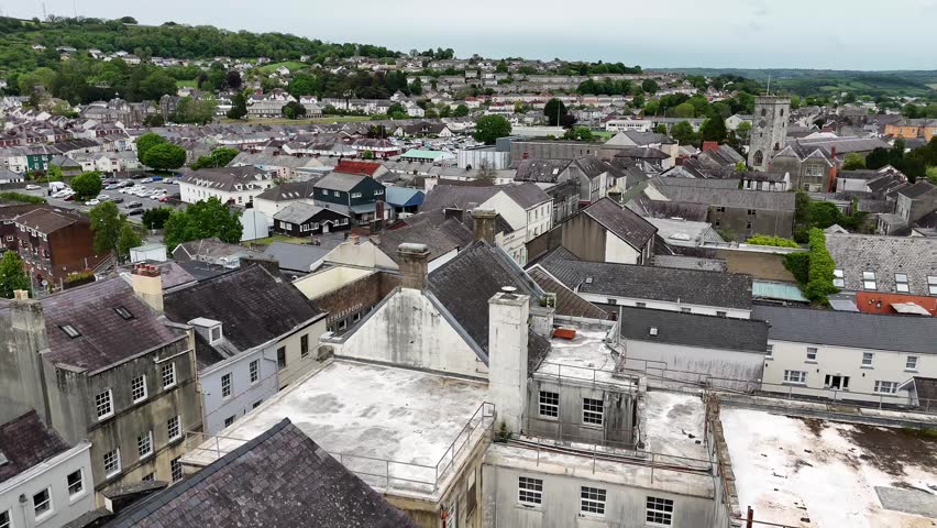 Aerial drone view flying over a small Welsh town toward a football pitch at golden hour.