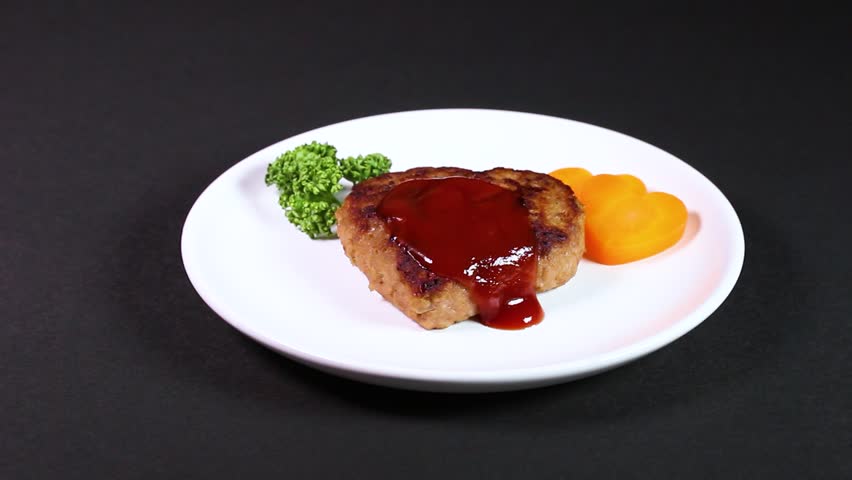 Heart-shaped hamburger steak served on a plate, rotating