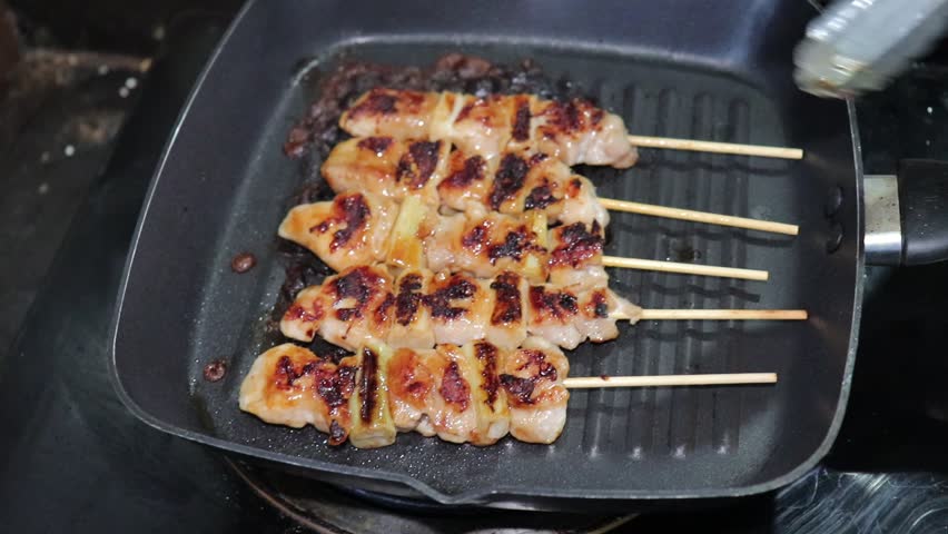 Grilled chicken skewers on a hot pan.