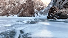 Low angle view from the surface of a frozen, cracked lake or river leading into a deep mountain canyon with towering, sheer rock walls dusted with snow and ice - Powered by Shutterstock - Get 15% off with code: PIKWIZARD15