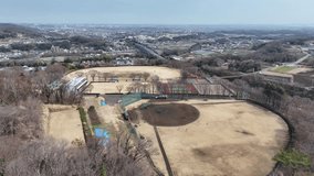 Drone circles above a baseball field in Hadano, Japan. Captures practicing youths, the field, and distant city and mountain views. Perfect for sports, education, or urban videos. - Powered by Shutterstock - Get 15% off with code: PIKWIZARD15