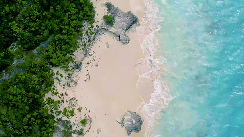 Aerial view of tropical beach with turquoise sea and white sand shoreline.