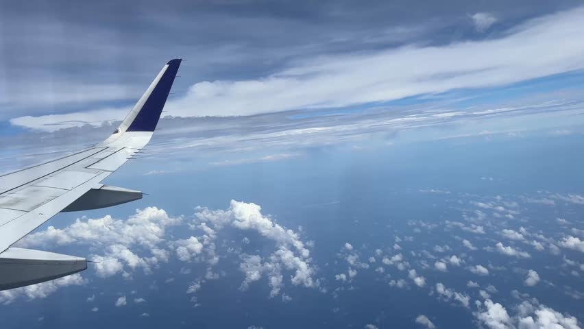 Aerial footage from airplane window showing wing and coastal landscape
