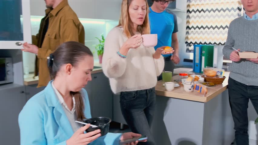 creative team enjoys breakfast together, creative professionals share breakfast with bright window lighting, team of creatives relaxes over coffee and discussion by sunny communal kitchen window